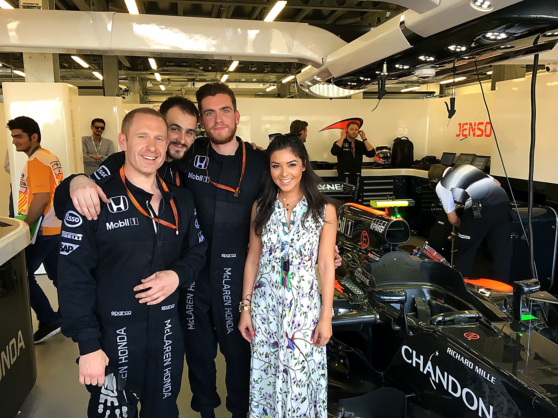 Kamila Verdiyeva with a Formula 1 team inside the garage beside the car