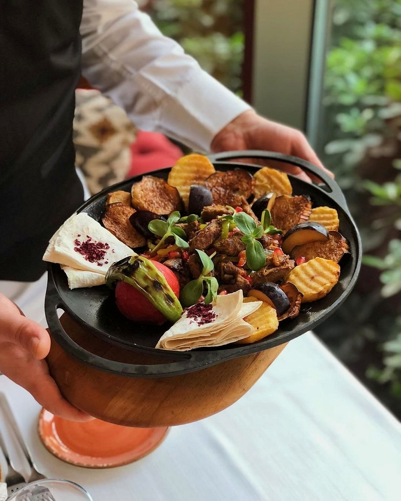 A cast-iron saj of chicken with aubergine, peppers and lavash carried to the table at Sumakh in Baku
