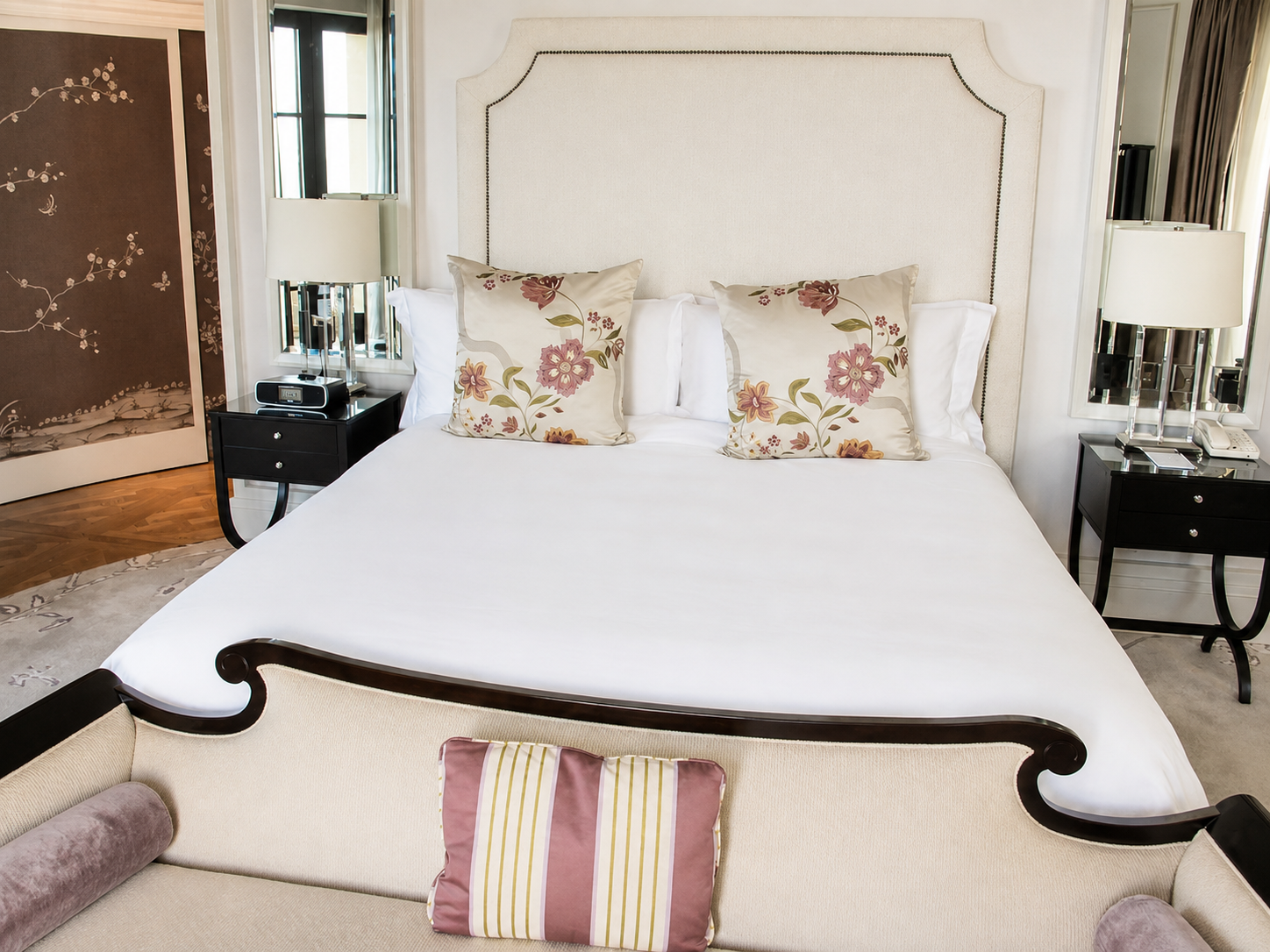 A five-star guest room with a linen headboard, crisp white bedding and hand-painted screen