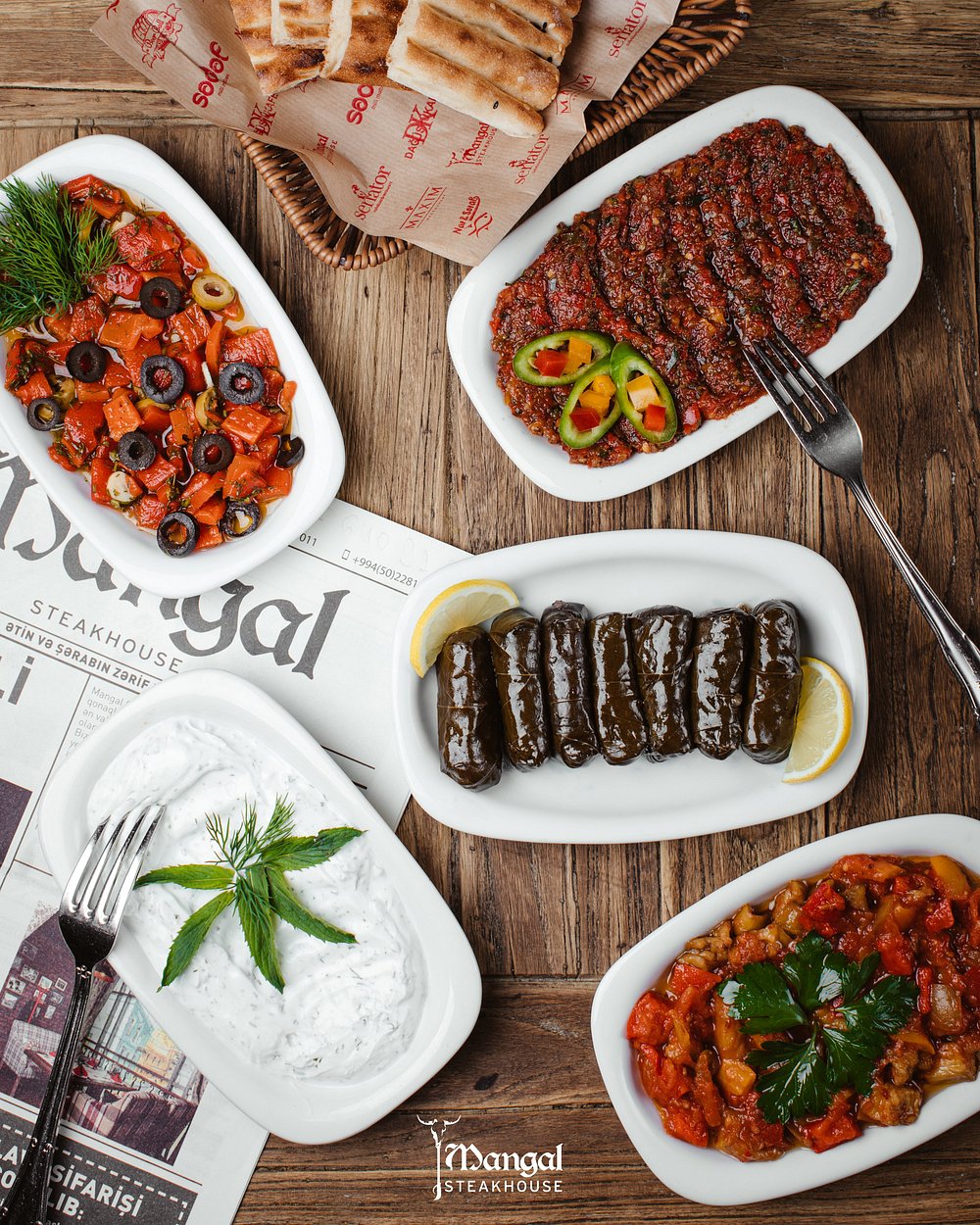 A spread of Azerbaijani mezze with grilled peppers, vine leaves, yoghurt and warm bread at Mangal in Baku