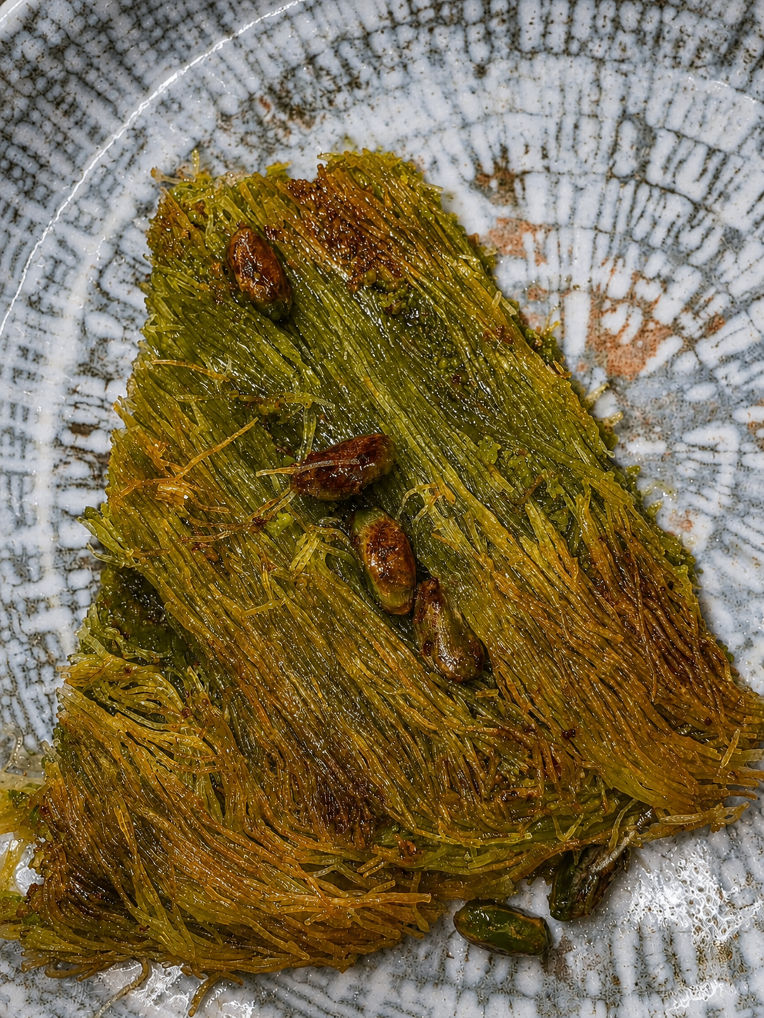 Pistachio kadayıf dessert with whole pistachios on a speckled ceramic plate at Günaydın in Baku