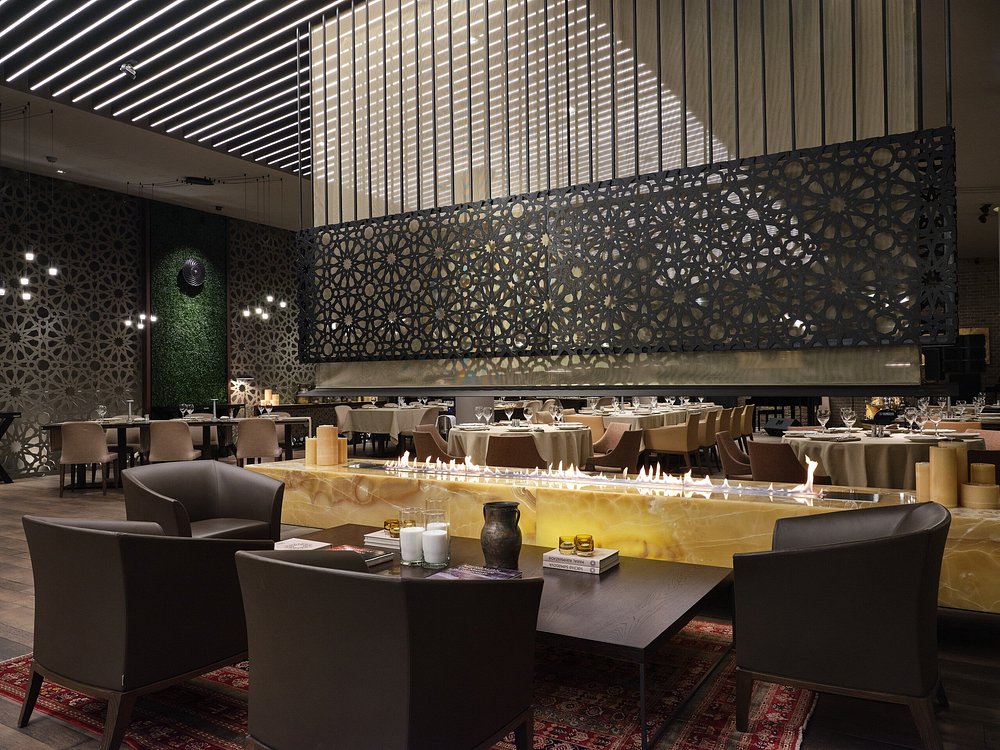 The dining hall at Shur in Baku — a long onyx fire table, geometric latticework screens and low leather armchairs