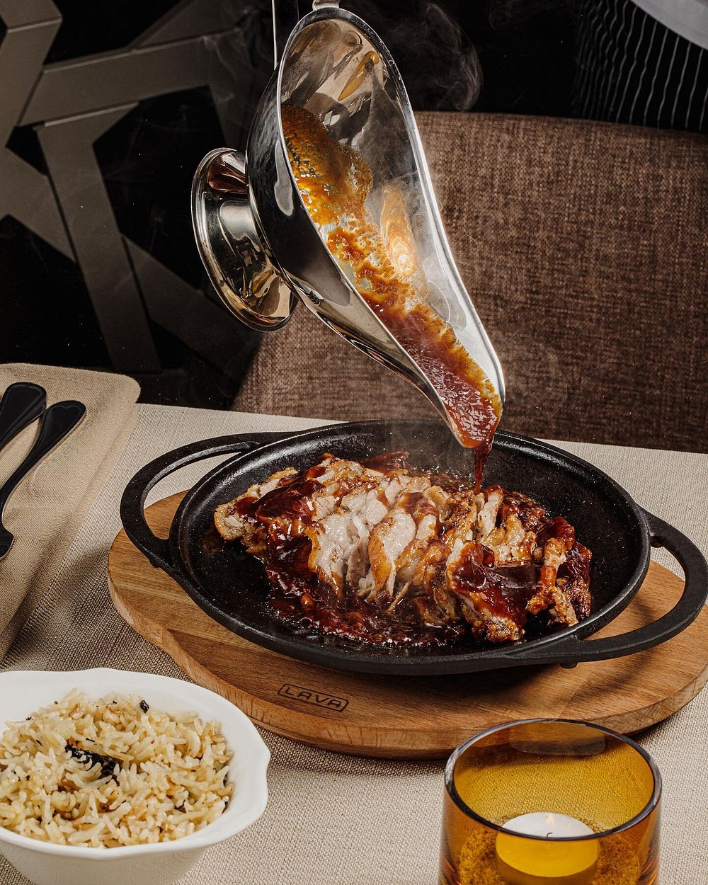 Sauce poured over a sizzling cast-iron dish of chicken with herbed rice at Shur in Baku