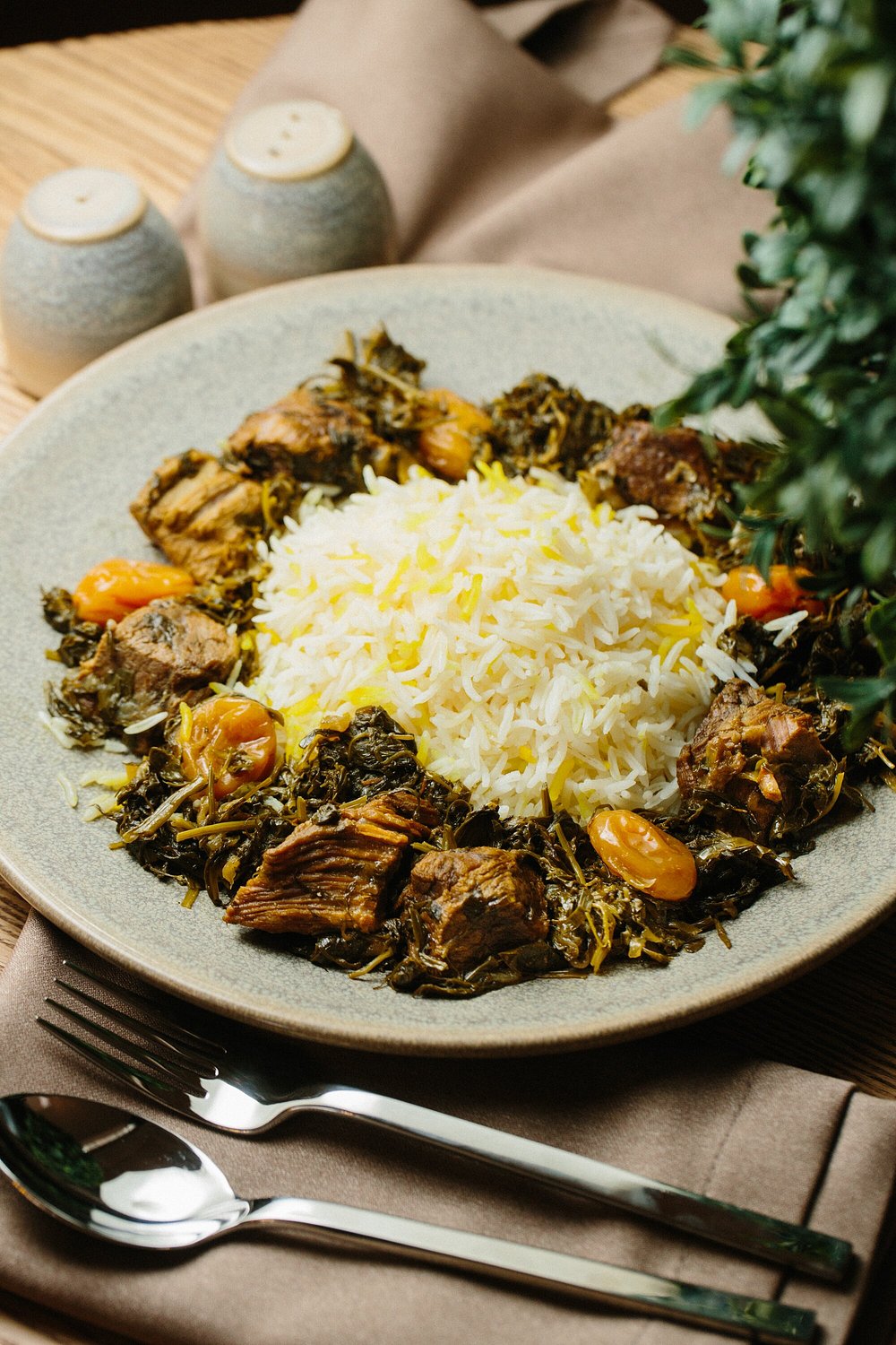 Sabzi plov: saffron rice ringed with slow-cooked lamb, herbs and dried apricots on a stoneware plate